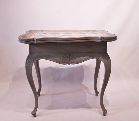 Grey painted rococo shaped tile-table decorated with different motives, from the 
1780s.
5000m2 showroom.