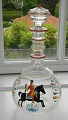 Carafe in glass 
from Holmegaard 
with enamel 
decoration with 
post rider in 
oldenburgske 
colors on ...