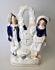 Staffordshire 
faience figure 
of boy and 
girl, standing 
by a clock, 
approx. 1850, 
England. ...