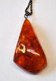 Large polished amber jewelery with seed capsules, 20th century. Length: 6 cm. With silver chain: ...