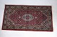 A real 
hand-knotted 
Persian rug 
dyed with 
reddish colors 
in the center 
and darker 
colors around 
...
