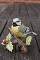 Sweet and charming figurine of biscuit, bird sitting on the branch of a rowanberry, in a mint ...