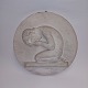 Round plaque in plaster with a motif of a crying boy on his knees, hiding his face in his hands. ...