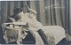Postkort: Ung kvinde læser morgenavisen i 1909