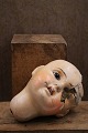 Old doll head 
in painted 
papier-mâché. 
The doll's 
head is broken 
on one side, 
with decorative 
...