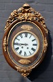 Wall clock, 
19th century. 
Brown painted 
case with 
gilded 
decorations in 
the form of 
rocailles ...