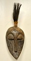 Small carved African wooden mask, mid 1900s. Top made of animal hair. H: 30 cm.