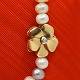 Charlotte Lynggard for Ole Lynggaard; A flower clasp, made of 14k gold with two brillant-cut ...