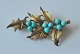 Gilded silver brooch with turquoises, 20th century. Stamped. L. 5.2 cm.
