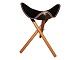 Foldable stool with black leather seat and wooden legs in a classic design in a beautiful ...