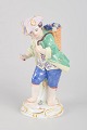 Meissen, grape boy figurine.Porcelain figurine depicting a boy carrying a basket filled with ...
